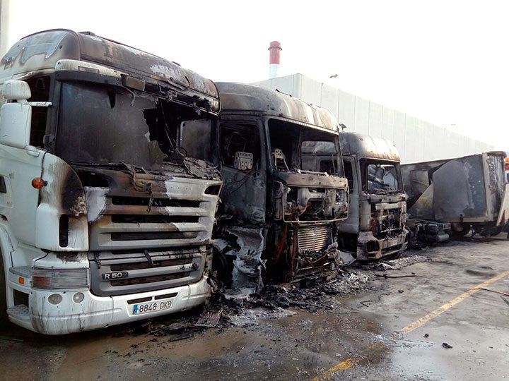 Arden siete camiones, una furgoneta y un autobús estacionados en la carretera de Logroño